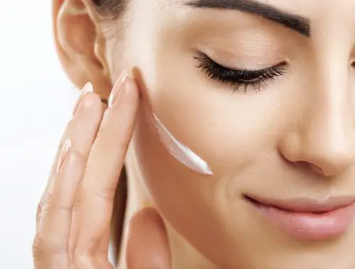 Woman putting facial moisturizer on face